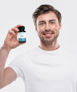 smiling man looking at camera holding supplement bottle